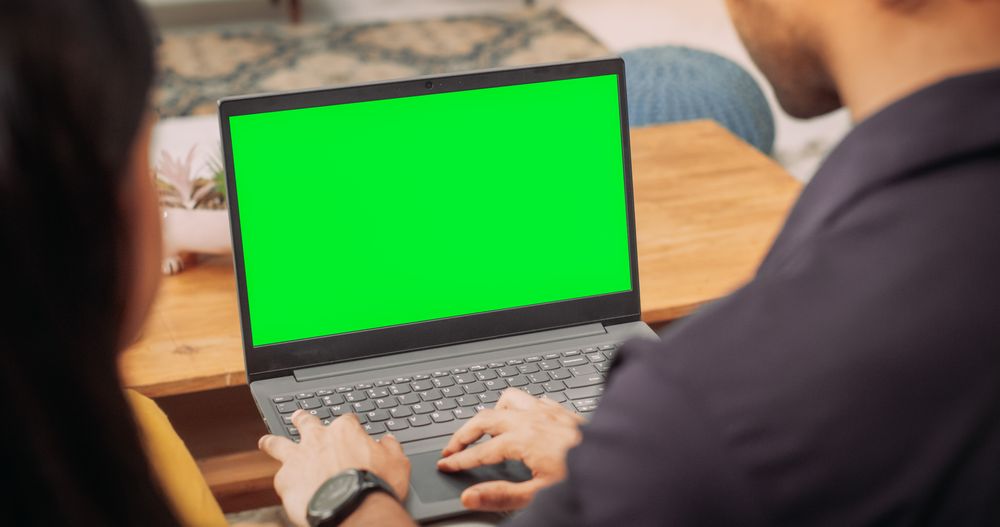 Young Couple Using Laptop with Green Screen:Browsing Websites for Clothing, Products Sales