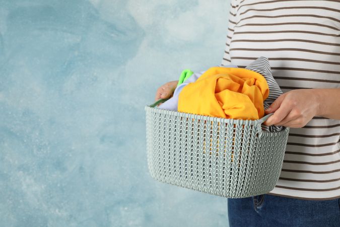 Young woman hold basket with clean clothes, space for text