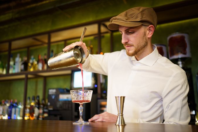 Bartender pouring cocktail into glassware from shaker