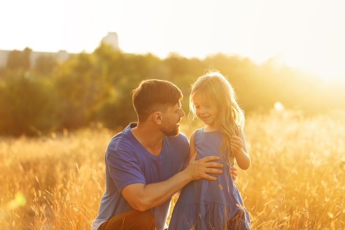 Man and daughter sitting in field of grass field
