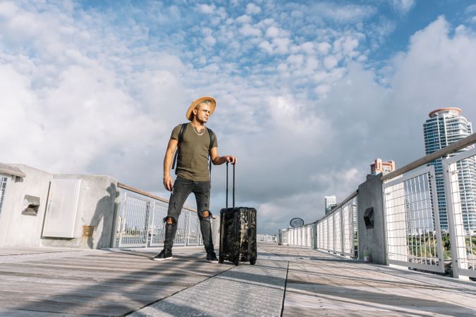 Traveler man with a hat walking with suitcase in the street
