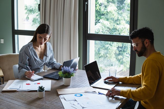 Focused colleagues working on laptops in coworking space