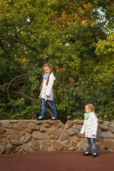 Girl balancing on wall as her sister follows along below