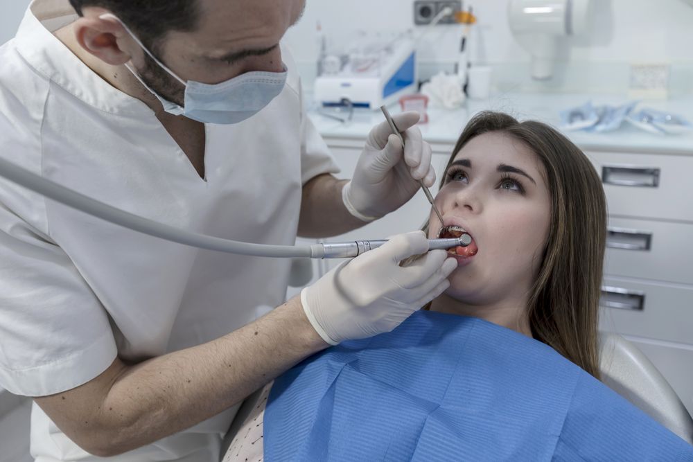 Dentist examining female teenager's teeth in clinic