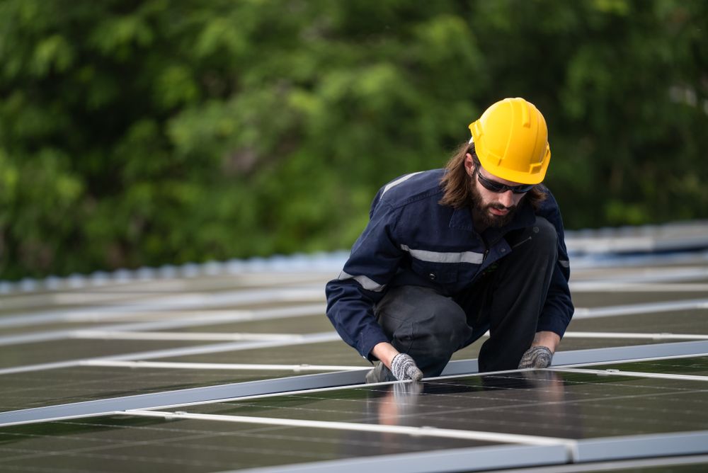 Male engineer checking solar cell  or photovoltaic cell by electronic device installed on the roof of the factory. Technician worker repair or inspect the system. Industrial renewable energy concept