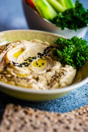 Close up of creamy hummus and vegetables on grey kitchen counter