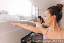 Women doing yoga in warrior pose at studio 4BaqR3