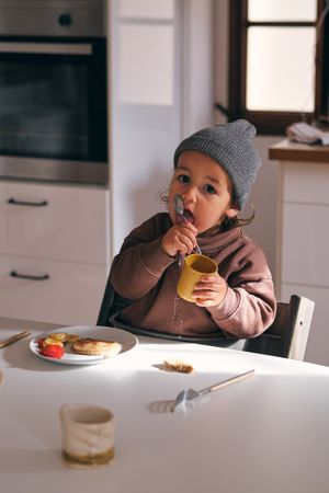 Cute boy licking spoon during breakfast