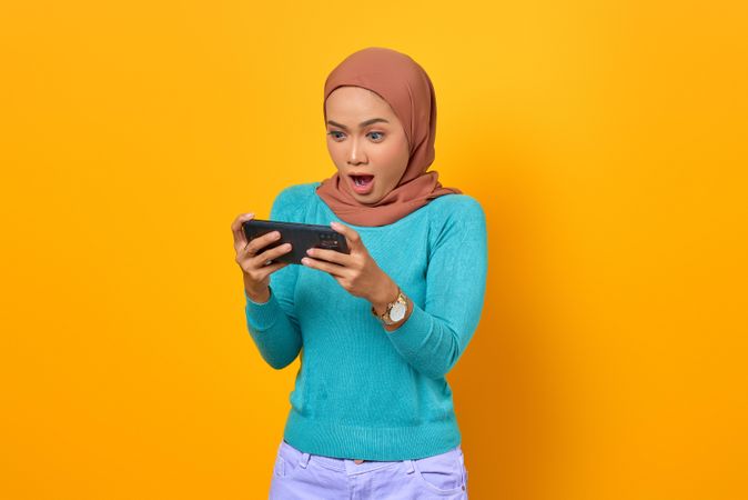 Surprised Muslim woman looking at her smartphone