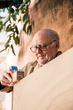 Older man shaping wood with plane tool