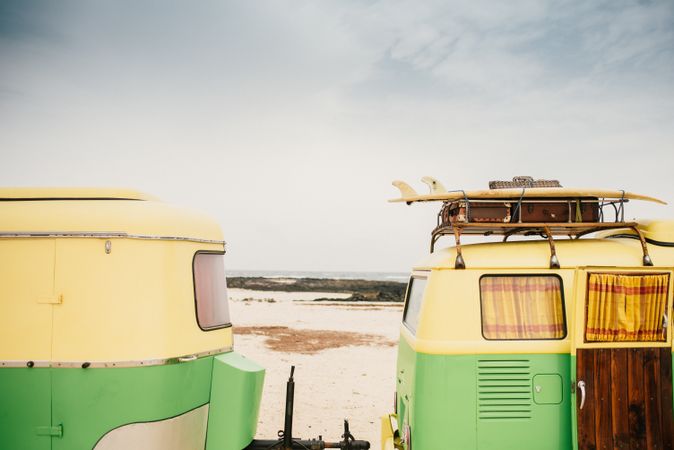 Colorful minibus with trailer parked on sandy shore in sunny day