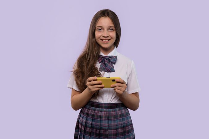 Girl in white shirt and plaid skirt holding smartphone
