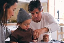 Crop parents with little son during breakfast in house