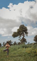 Man training yoga on meadow