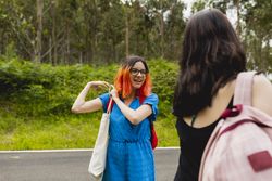 Two young women chat animatedly before starting a walk in a rural area close to nature, in summer