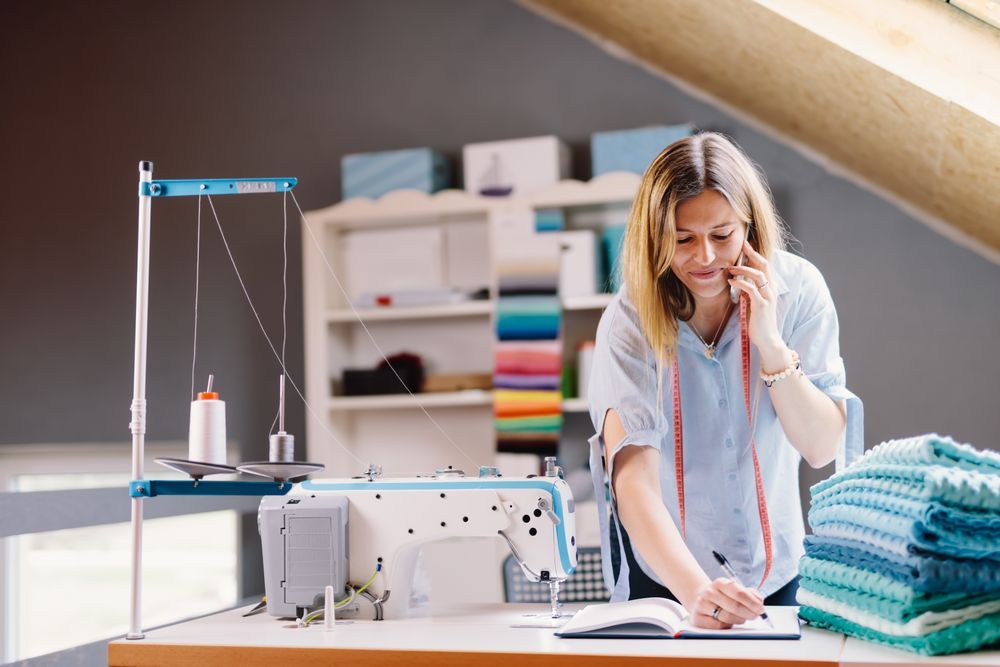 Cheerful seamstress talking on smartphone