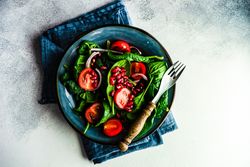 Top view bowl of organic salad with spinach and pomegranate
