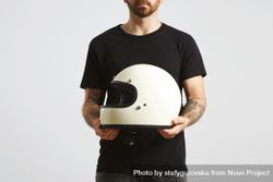 Man in plain dark t-shirt and dark jeans holding motorcycle helmet 0WKgx0