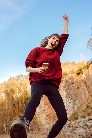 Young woman with smartphone dancing