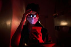 Confused doctor in mask looking at screen of cellphone