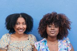 Portrait of two women standing on a blue wall