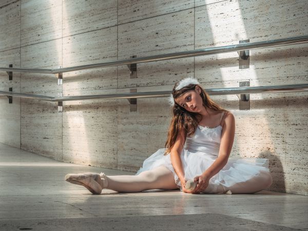 Ballerina sitting on floor stretching graceful leg