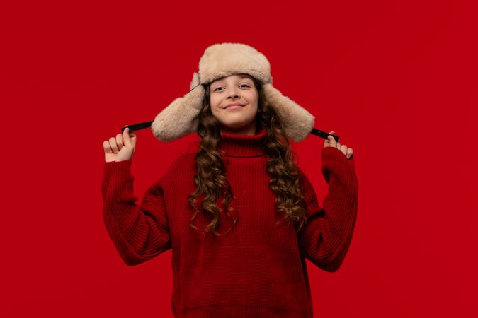 Happy girl in fur hat confidently holds ear flaps hat