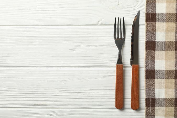 Tablecloth and cutlery on wooden background, space for text