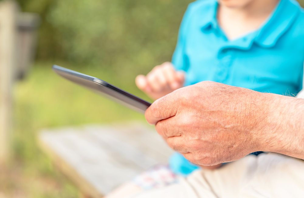 Grandfather hands using tablet with grandchild