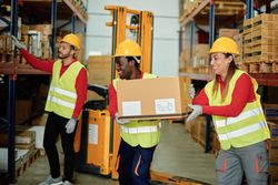 Positive diverse workers unloading boxes in warehouse