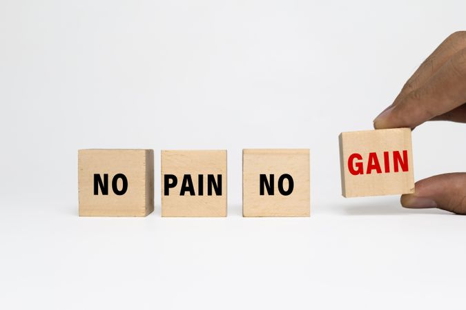 male hand put a wooden blocks with no pain no gain words isolated on blank background