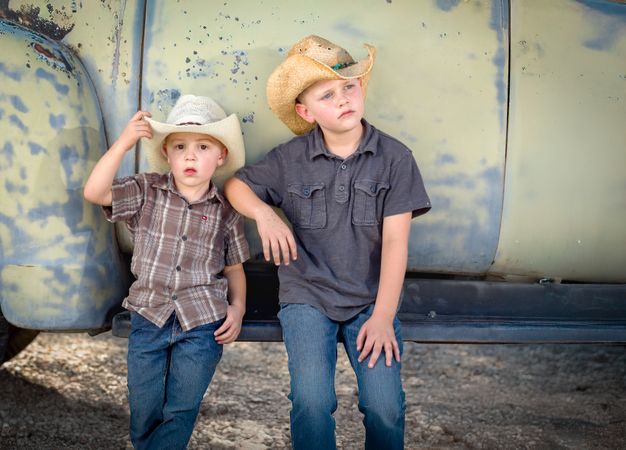 Two Young Boys Wearing Cowboy Hats Leaning Against Antique Truck.
