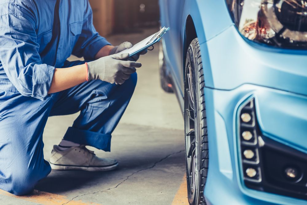 Car mechanic crushing next to car doing a check