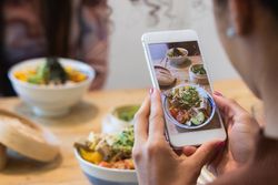 Anonymous woman taking photo of dish in restaurant