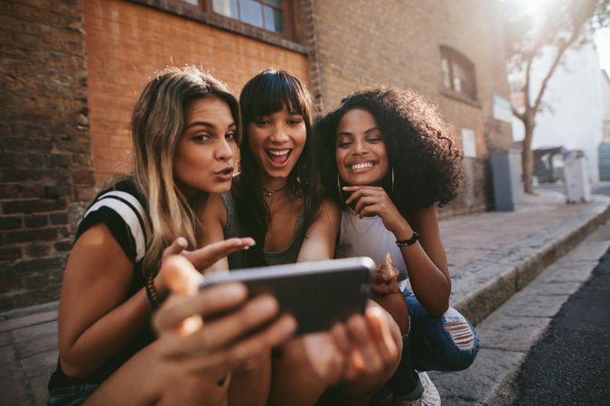 Joyful group of females smiling for selfie outdoors