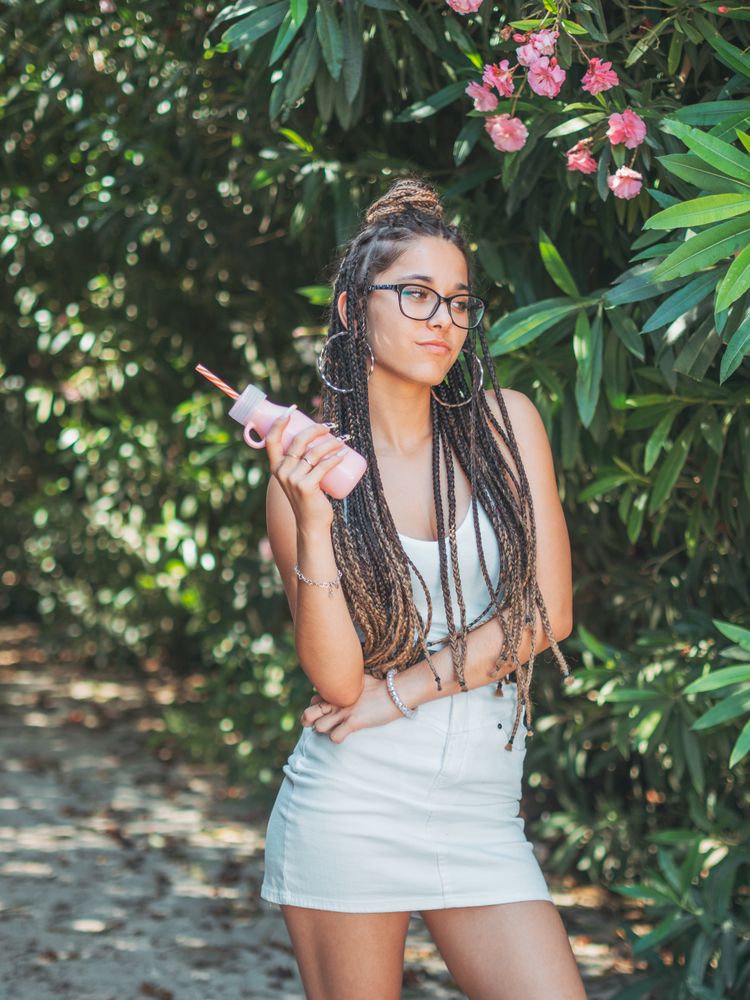 Stylish young woman with dreadlocks and beverage