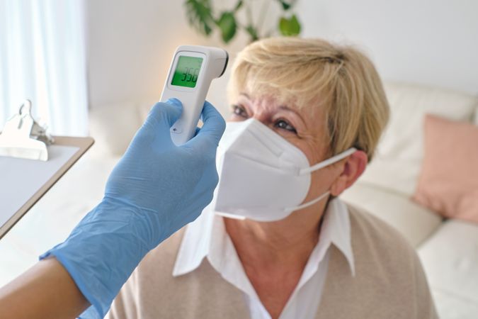 Crop physician measuring temperature of patient with infrared thermometer