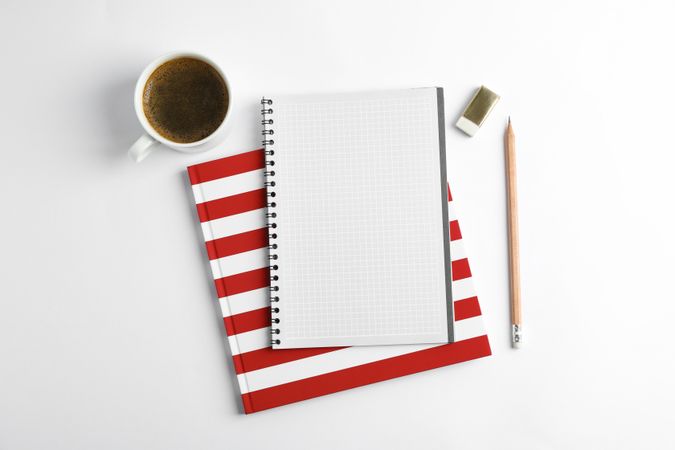 Cup of coffee with copybooks and pencil on blank background, top view