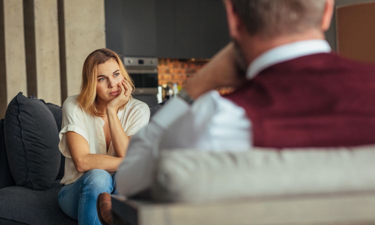 Upset woman sitting on sofa during psychotherapy session