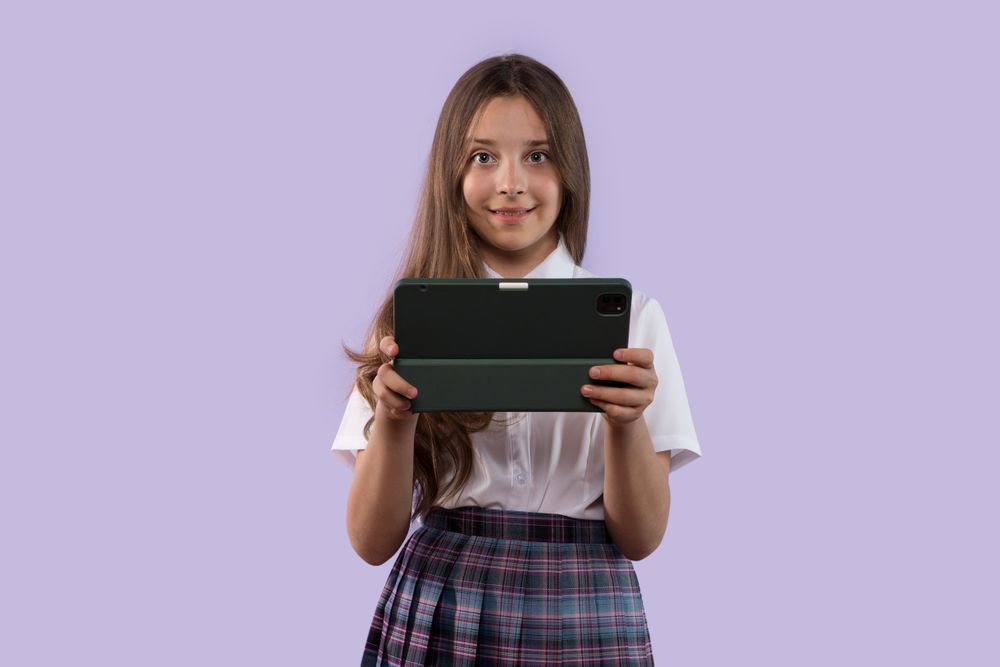 Young girl holding tablet and smiling with focus.