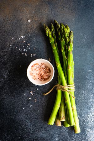 Wrapped bunch of raw asparagus on counter with Himalayan salt