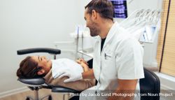 Dentist comforting his female patient before dental procedure bxYrn0