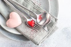 Valentine Day holiday card concept with red glitter and hearts adorning grey plates