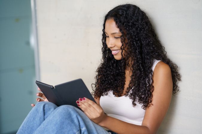 A Young Woman is Found Enjoying a Book in a Cozy Indoor Setting, Immersed in Reading Delightfully
