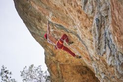 Faceless strong climber holding onto rock while hanging on rope