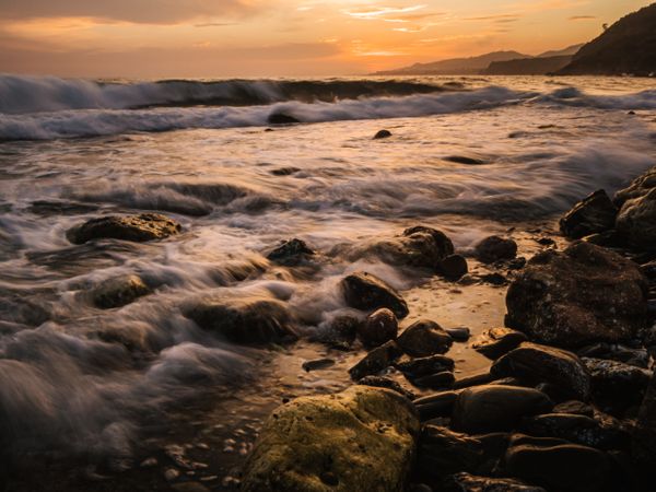 Stony seashore and waves at beautiful sunset