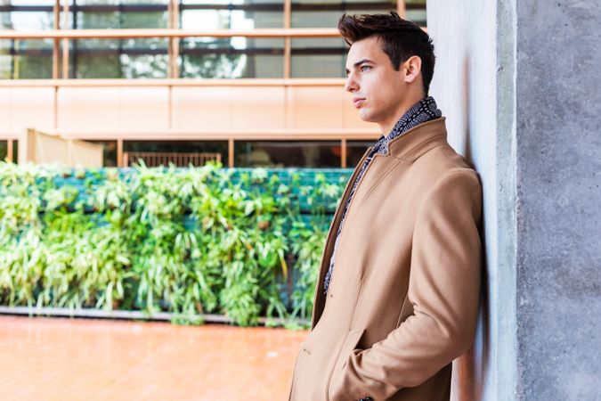 Man wearing winter clothes leaning on wall outside