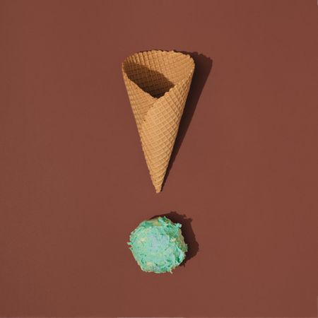 Waffle cone with scoop of ice cream on brown background