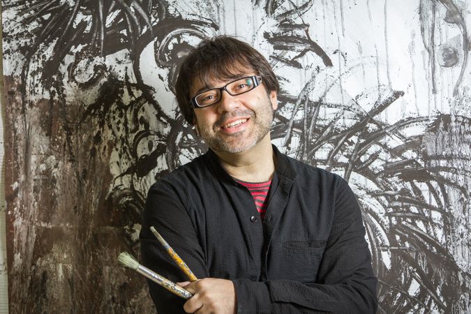 Painter artist posing in front of paint