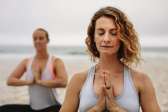 Fitness women doing yoga at the beach on a cloudy morning